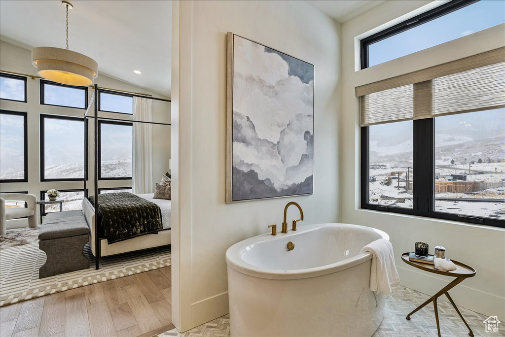 Bathroom with a soaking tub, connected bathroom, and wood finished floors