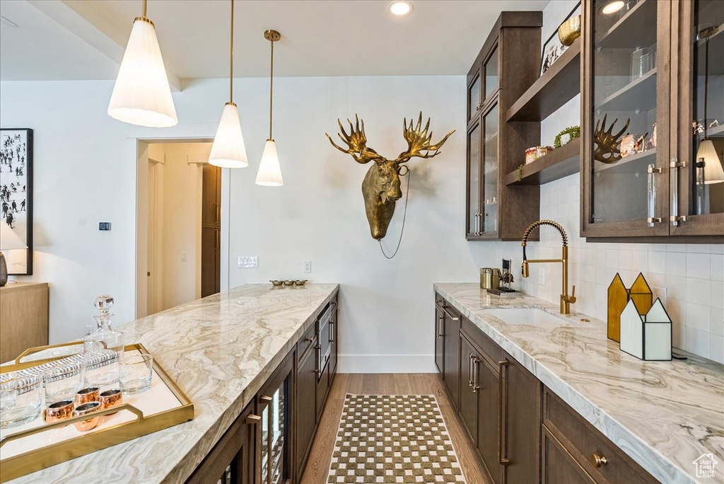 Kitchen featuring dark brown cabinetry, light wood-type flooring, tasteful backsplash, decorative light fixtures, and recessed lighting