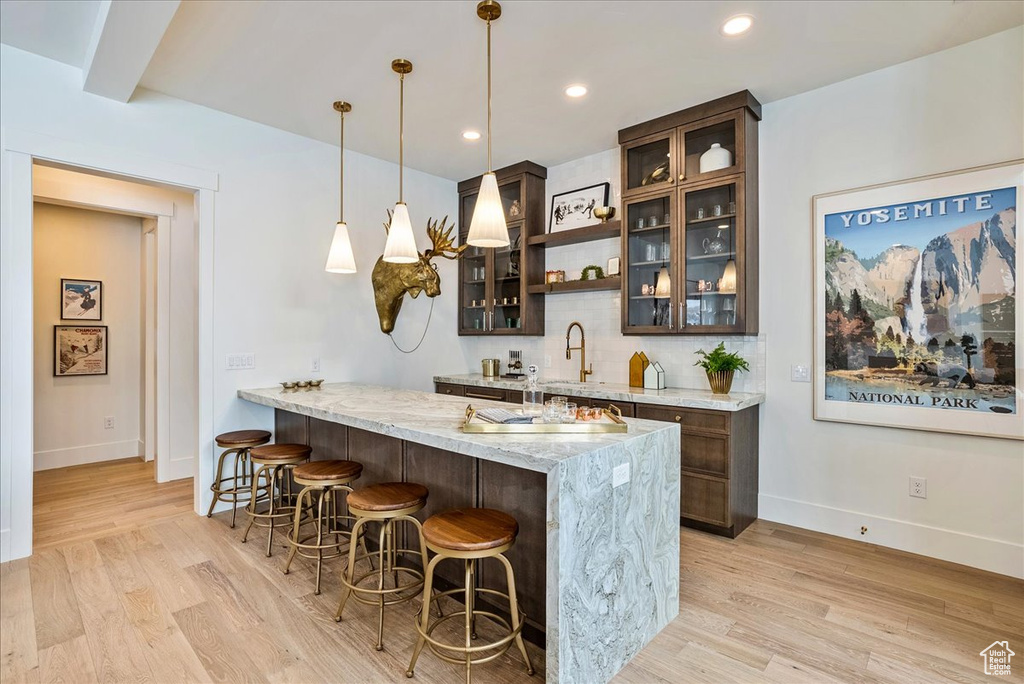 Bar featuring light wood finished floors, pendant lighting, backsplash, and recessed lighting