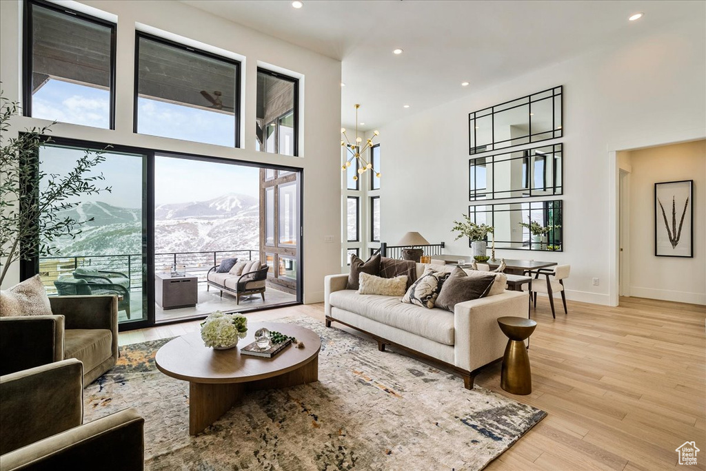 Living room featuring a towering ceiling, a mountain view, light wood-style flooring, a chandelier, and recessed lighting