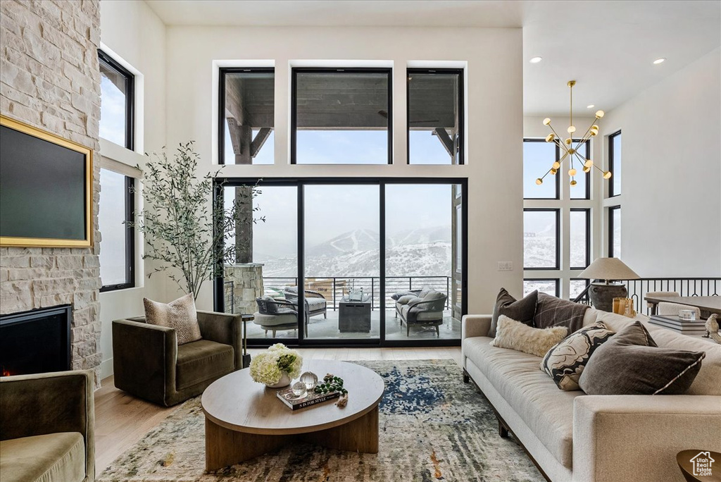 Living area featuring a mountain view, a fireplace, wood finished floors, plenty of natural light, and a towering ceiling
