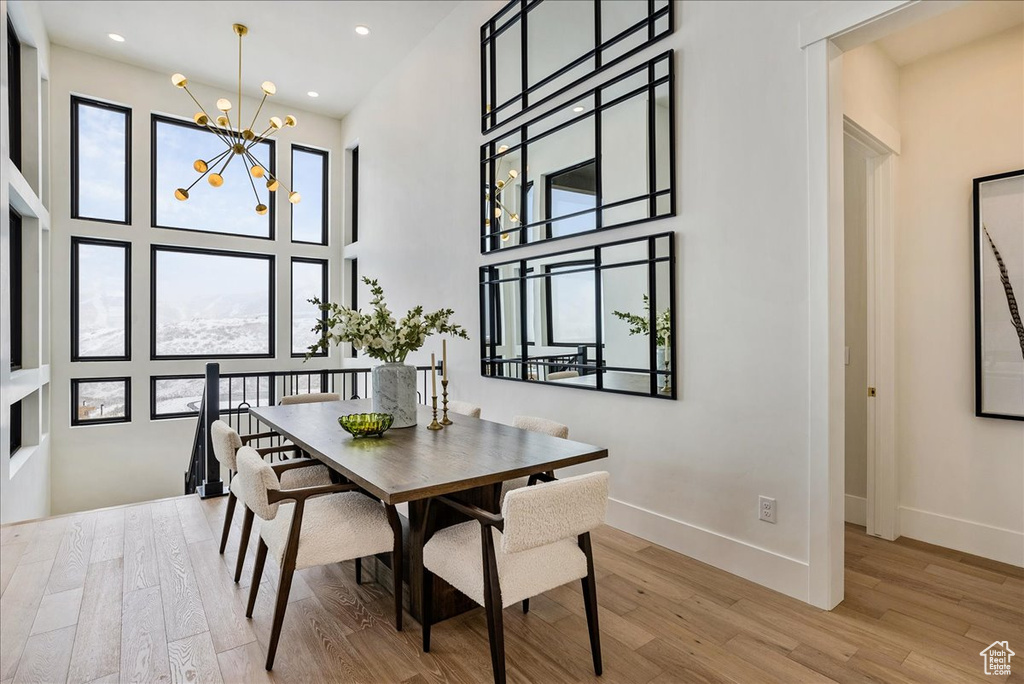 Dining area featuring wood finished floors, a chandelier, a high ceiling, and recessed lighting