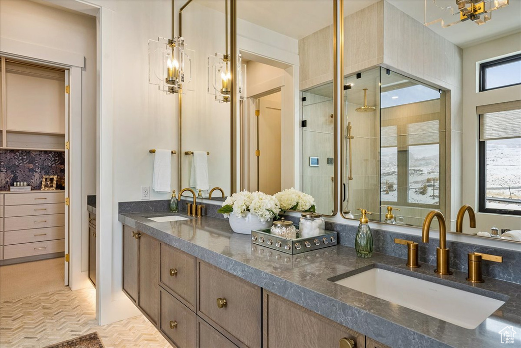 Bathroom featuring double vanity, a shower with shower door, and a chandelier