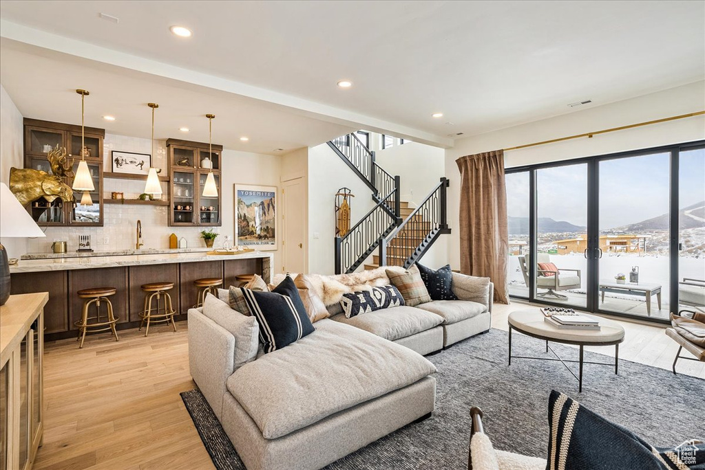 Living area with a mountain view, light wood-style floors, recessed lighting, wet bar, and stairs
