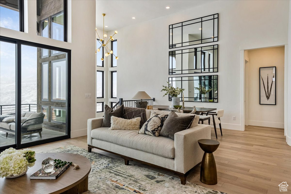 Living room featuring plenty of natural light, a towering ceiling, wood finished floors, and recessed lighting