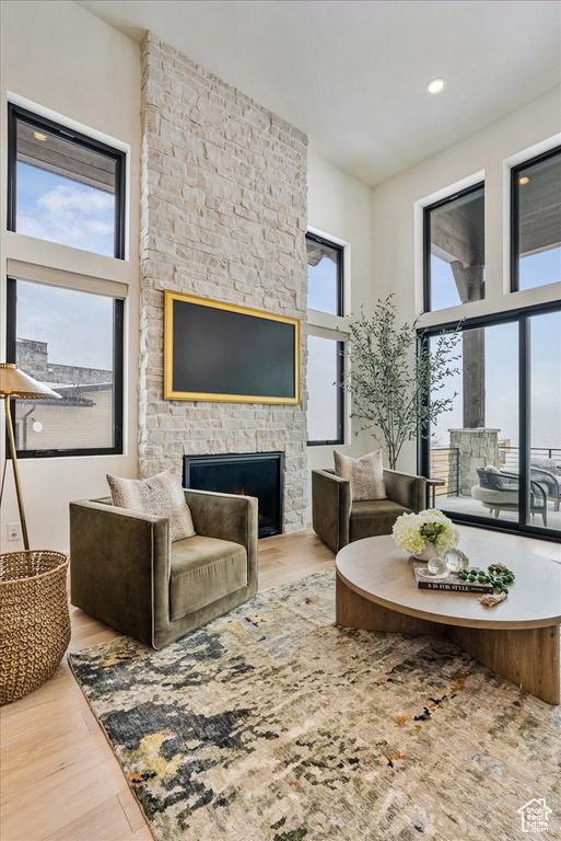 Living area with a fireplace, wood finished floors, recessed lighting, and a towering ceiling