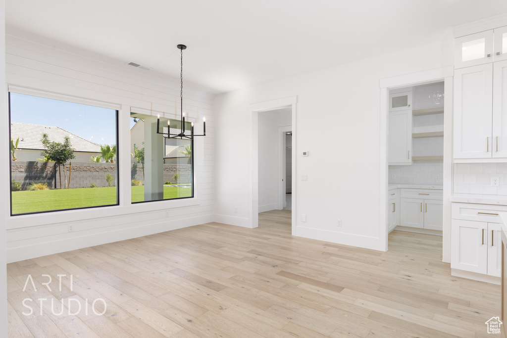 Unfurnished dining area featuring a chandelier and light wood finished floors