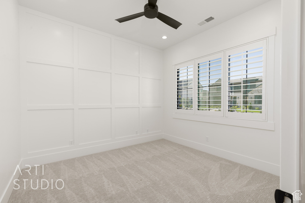 Empty room featuring light carpet, ceiling fan, recessed lighting, and a decorative wall
