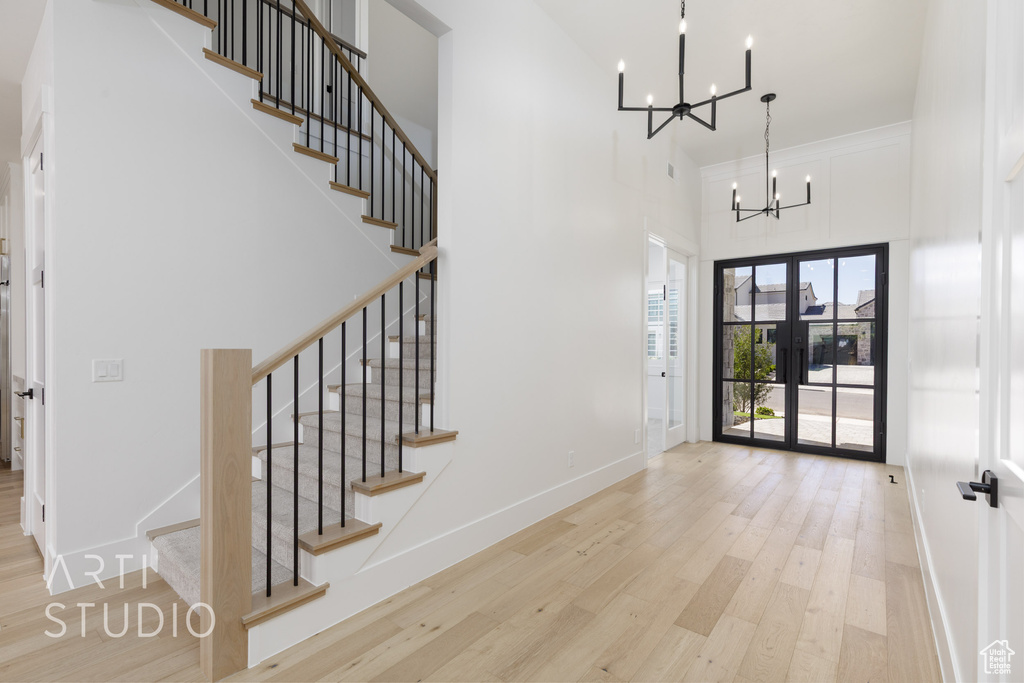 Foyer entrance featuring a chandelier, a high ceiling, wood finished floors, and stairway
