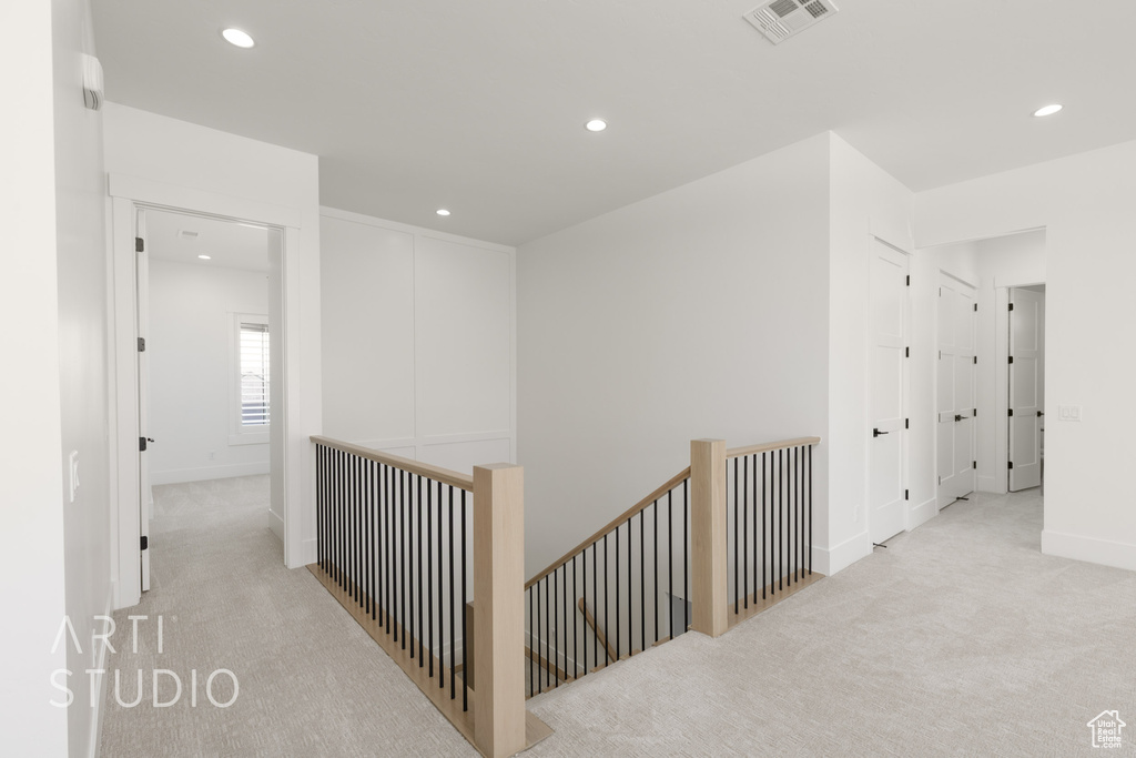 Hallway with an upstairs landing, light carpet, and recessed lighting