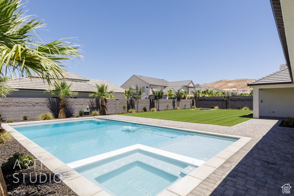 View of pool featuring a fenced backyard, a pool with connected hot tub, and a patio