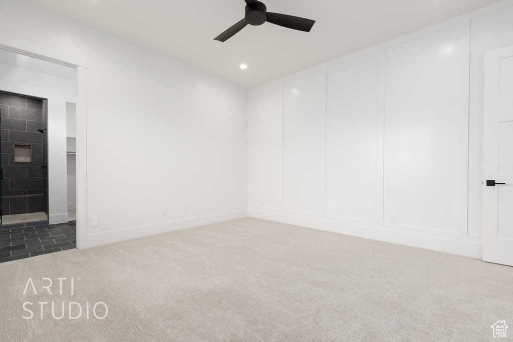 Carpeted spare room featuring a ceiling fan, recessed lighting, and a decorative wall