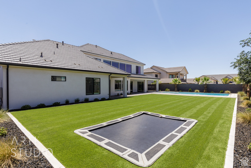 Back of house with stucco siding, a fenced backyard, and a patio area