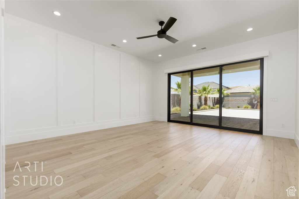 Empty room with a decorative wall, light wood-style flooring, ceiling fan, and recessed lighting
