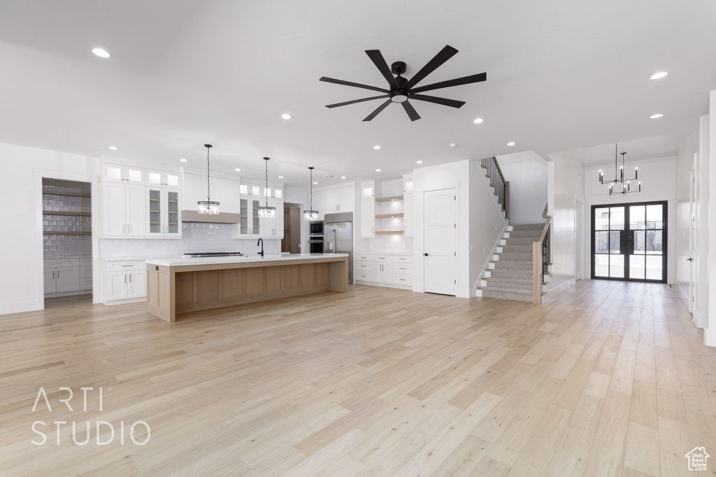 Kitchen with open floor plan, decorative backsplash, a chandelier, light countertops, and light wood-type flooring
