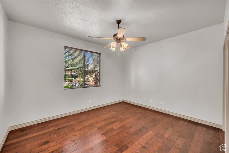Unfurnished room featuring dark wood-style flooring and ceiling fan