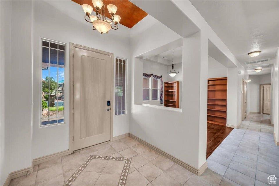 Tiled foyer entrance featuring baseboards and a chandelier