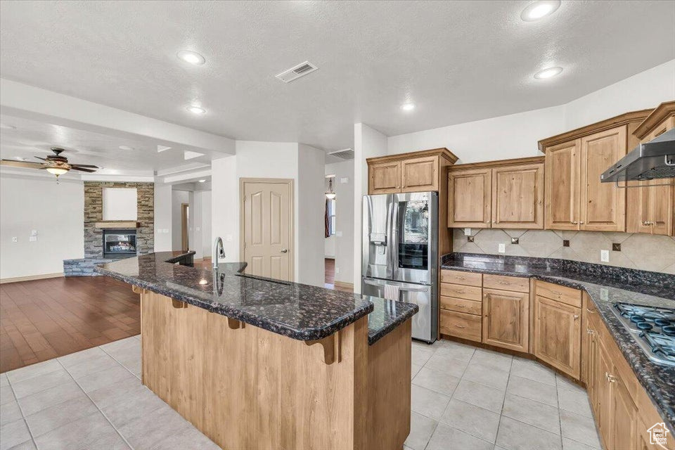 Kitchen with stainless steel appliances, open floor plan, a breakfast bar, ceiling fan, and recessed lighting