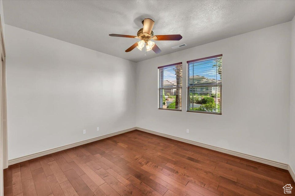 Unfurnished room featuring dark wood-type flooring and a ceiling fan
