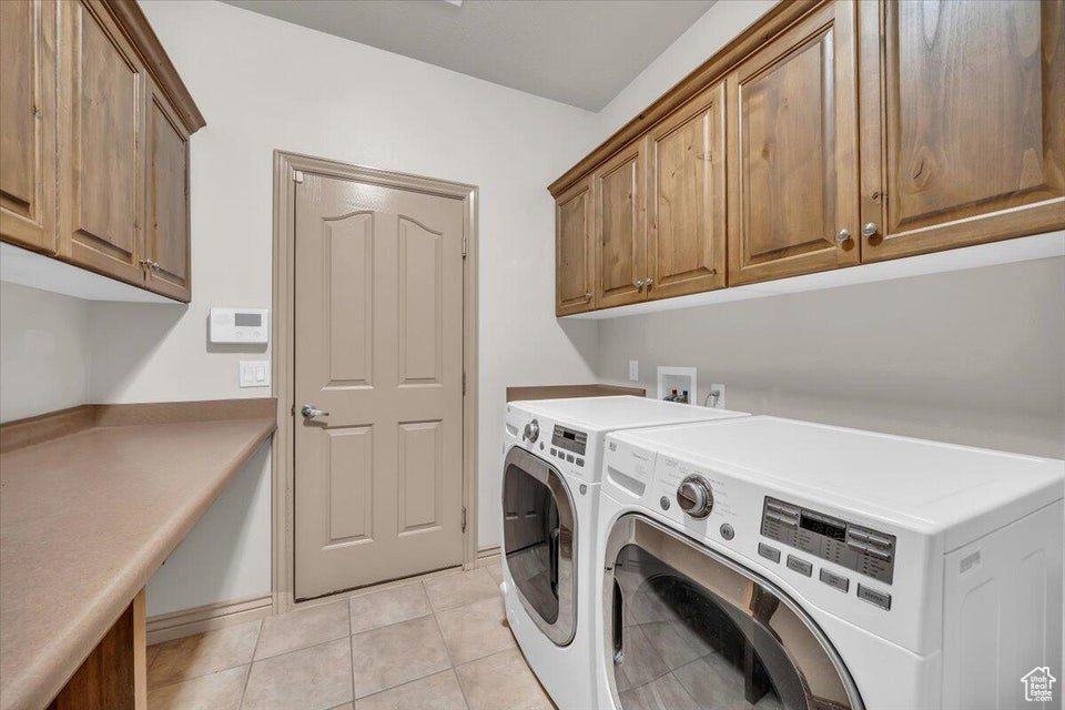 Washroom with cabinet space, independent washer and dryer, and light tile patterned floors