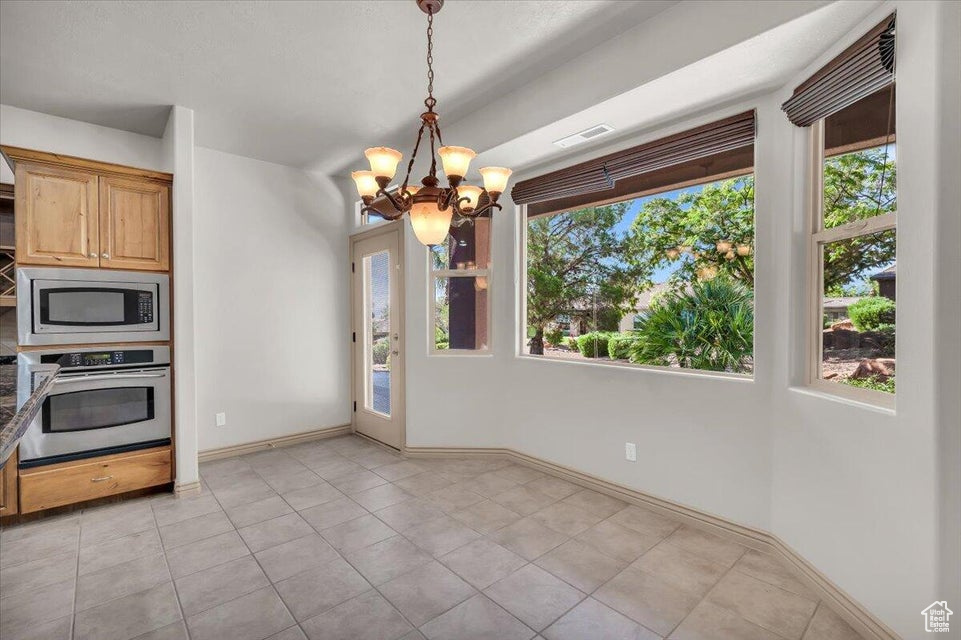 Kitchen featuring stainless steel appliances, a chandelier, hanging light fixtures, and light tile patterned floors