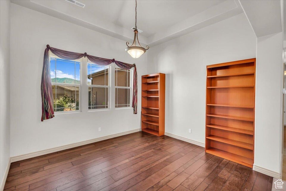 Empty room featuring dark wood-style flooring and baseboards