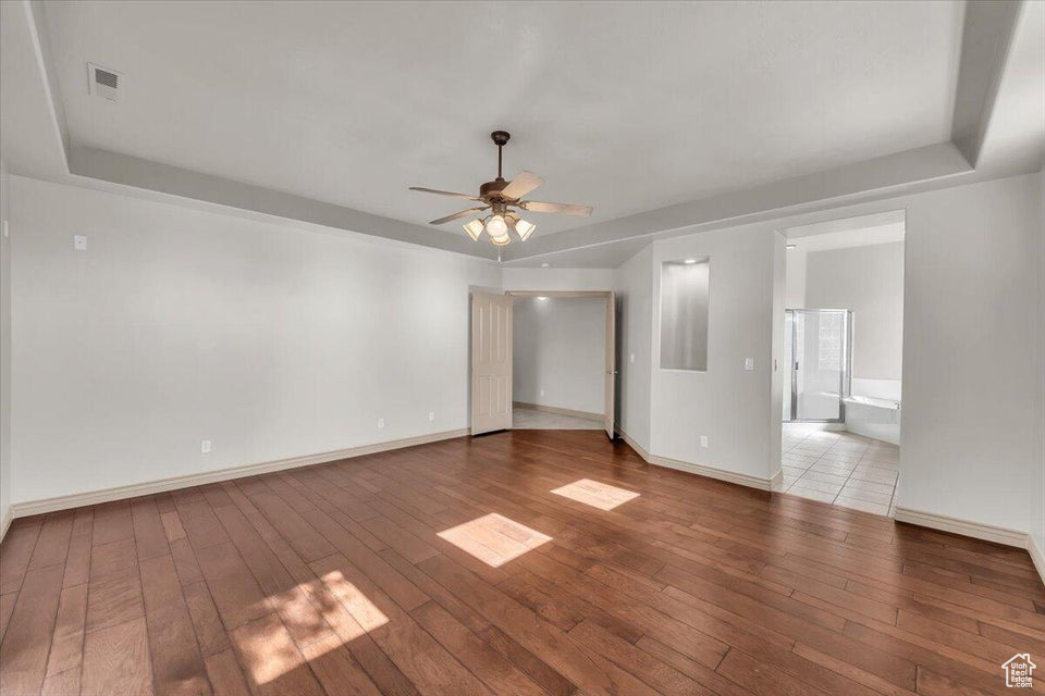 Spare room featuring hardwood / wood-style flooring, a ceiling fan, and a raised ceiling