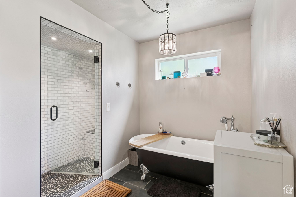 Full bathroom with a freestanding tub, a stall shower, tile patterned flooring, and a chandelier