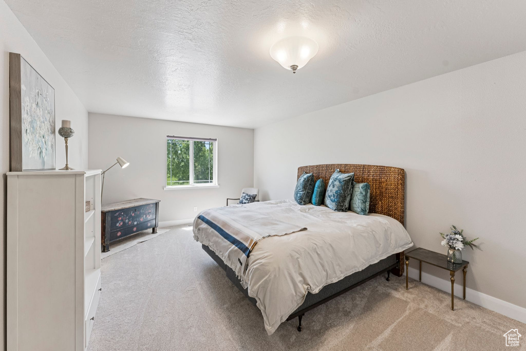 Carpeted bedroom featuring baseboards and a textured ceiling