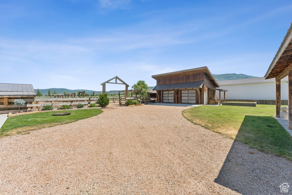 View of green lawn with a detached garage, a mountain view, and an outdoor structure
