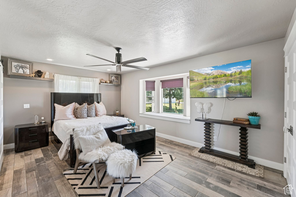 Bedroom with multiple windows, wood finished floors, a textured ceiling, ceiling fan, and recessed lighting