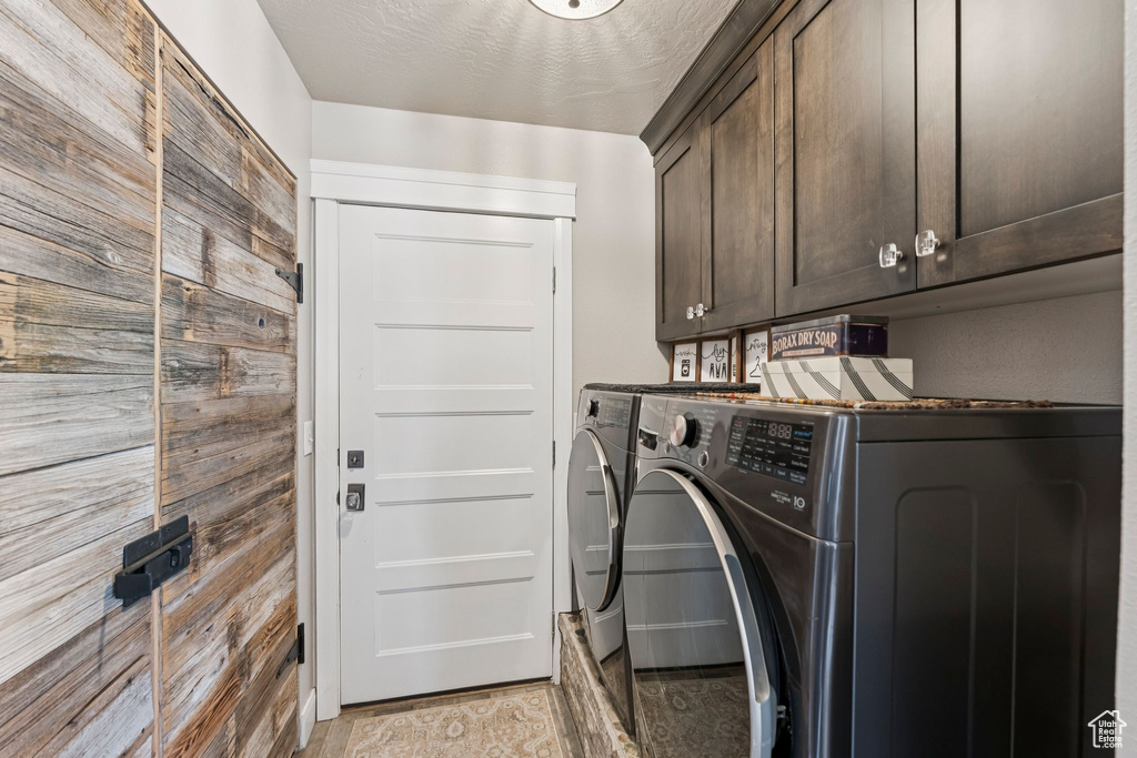 Laundry room featuring cabinet space, separate washer and dryer, and wood walls
