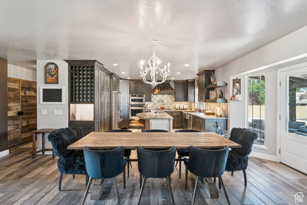 Dining room featuring a chandelier, wood finished floors, recessed lighting, and a textured ceiling