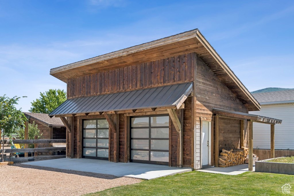View of front of home featuring a garage, an outdoor structure, and a metal roof
