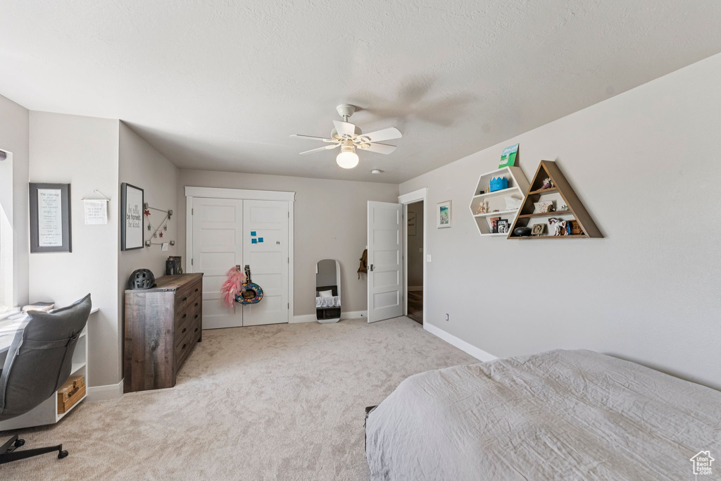 Bedroom featuring light carpet, ceiling fan, and a closet