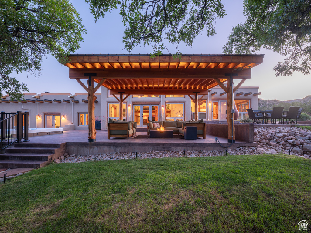 Back of property at dusk featuring outdoor lounge area, a yard, a deck, a pergola, and a metal roof