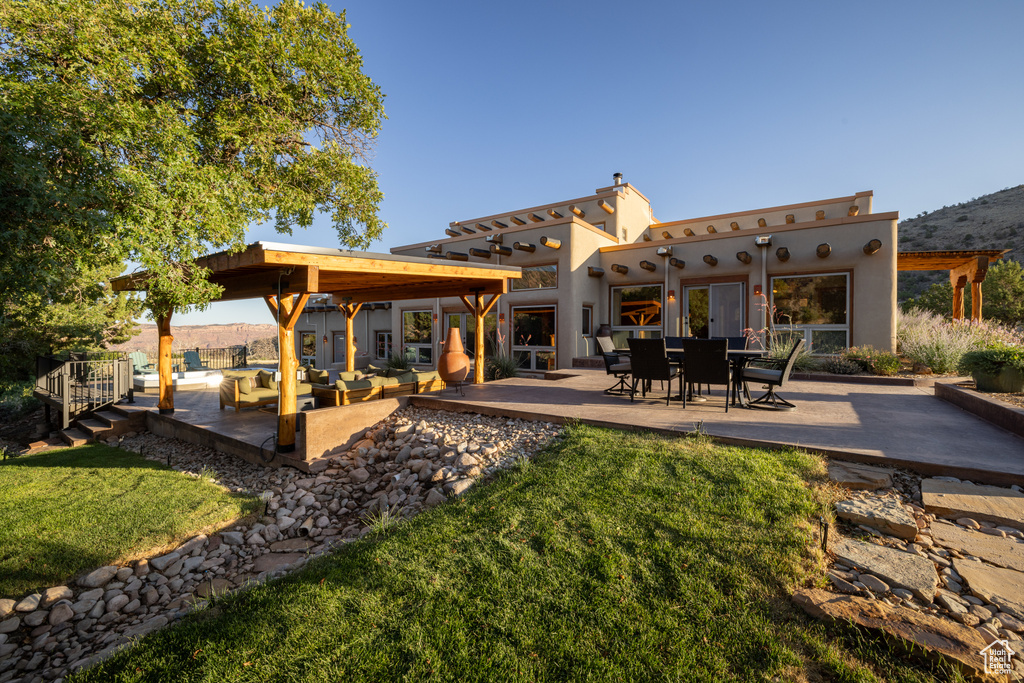 Rear view of house with a patio area, a lawn, an outdoor hangout area, and stucco siding