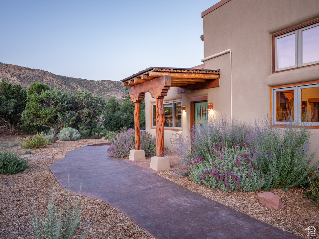 View of side of property featuring stucco siding, a mountain view, and a patio