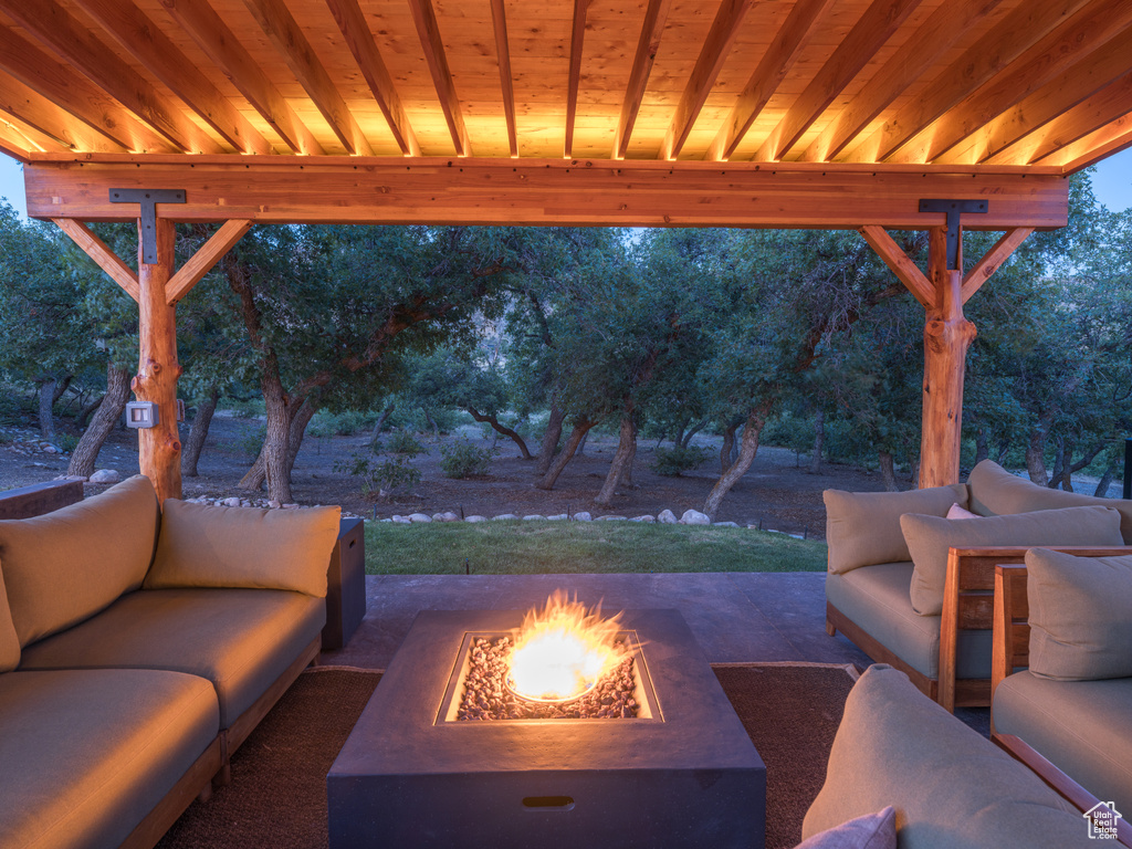 View of patio with an outdoor living space with a fire pit and view of wooded area