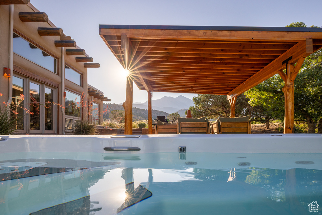 View of pool featuring a hot tub, french doors, and a mountain view
