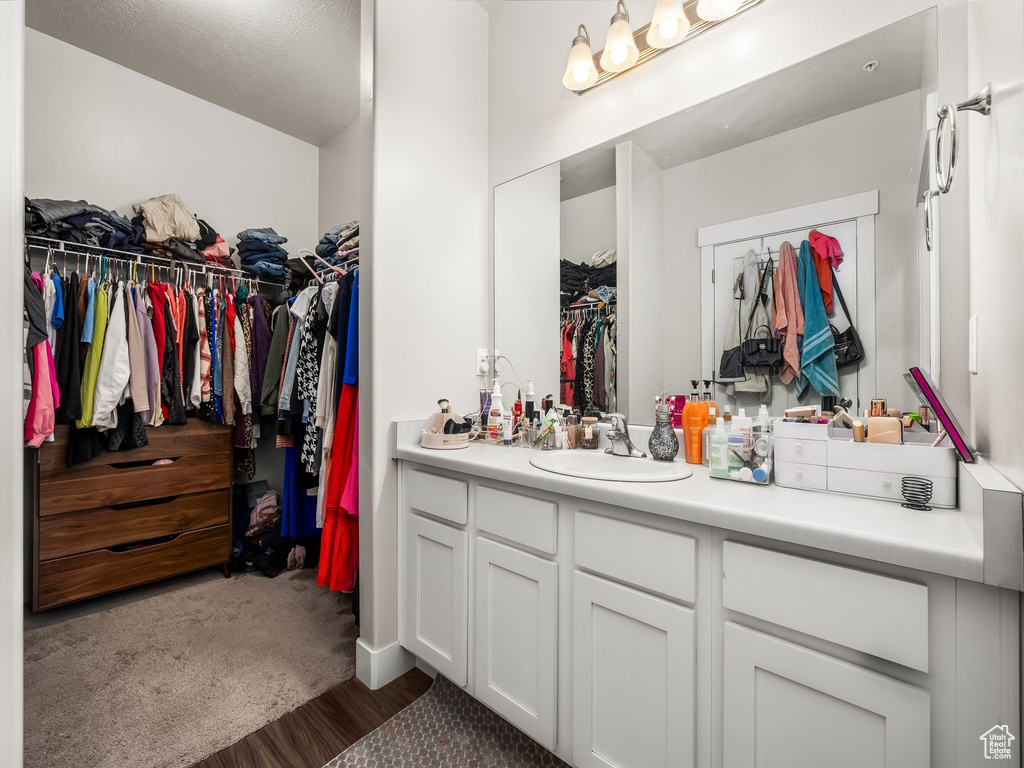 Bathroom with vanity, a walk in closet, and wood finished floors