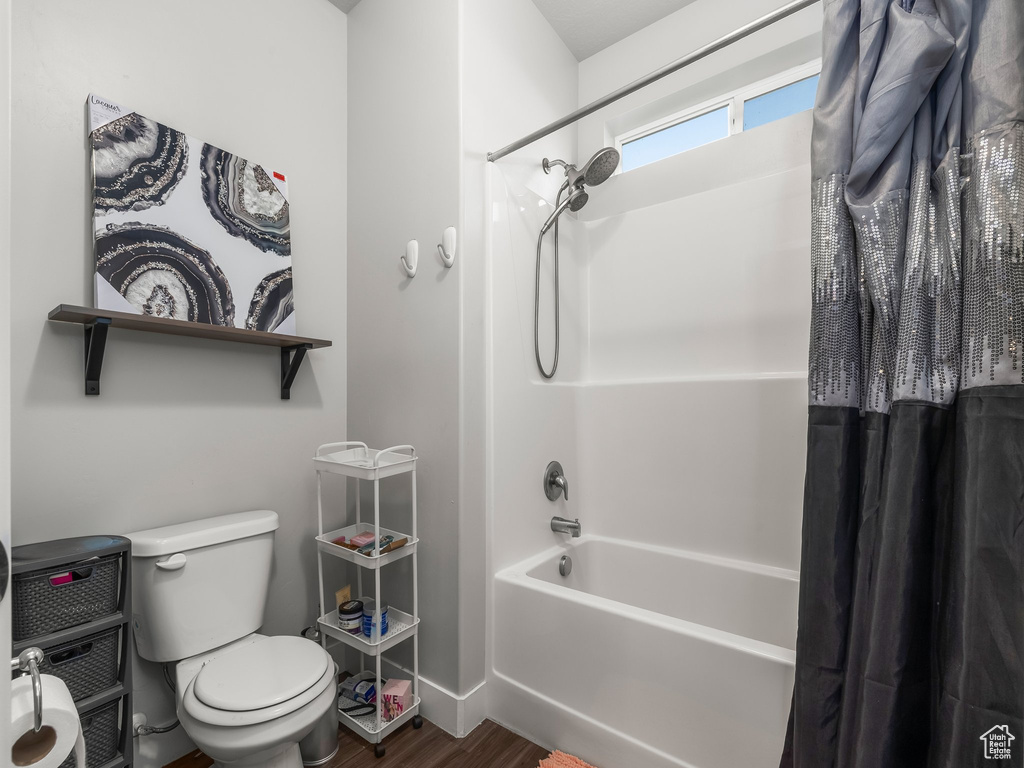 Bathroom with shower / bath combination with curtain and wood finished floors