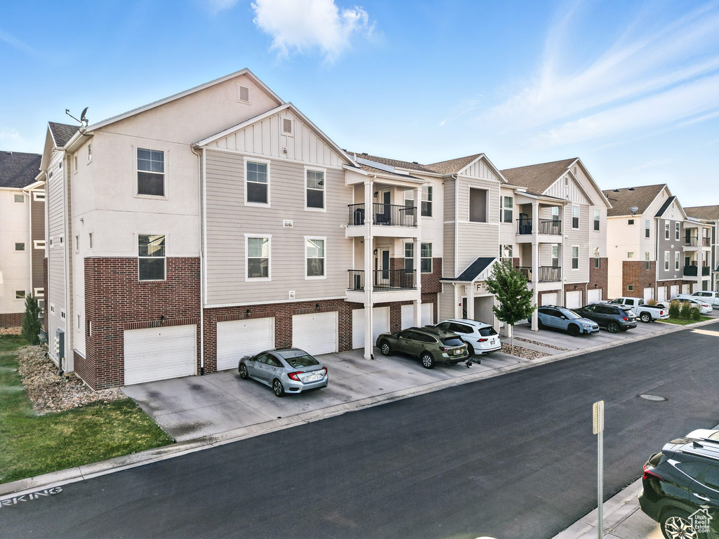 View of building exterior with a residential view, an attached garage, and driveway
