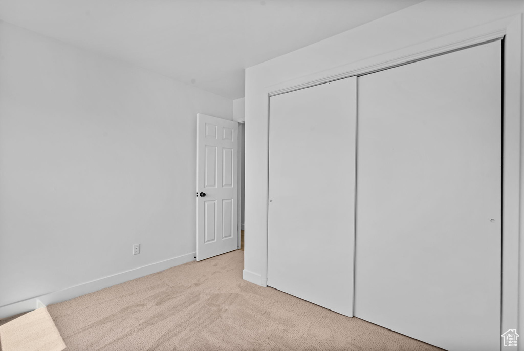 Unfurnished bedroom featuring light carpet and a closet
