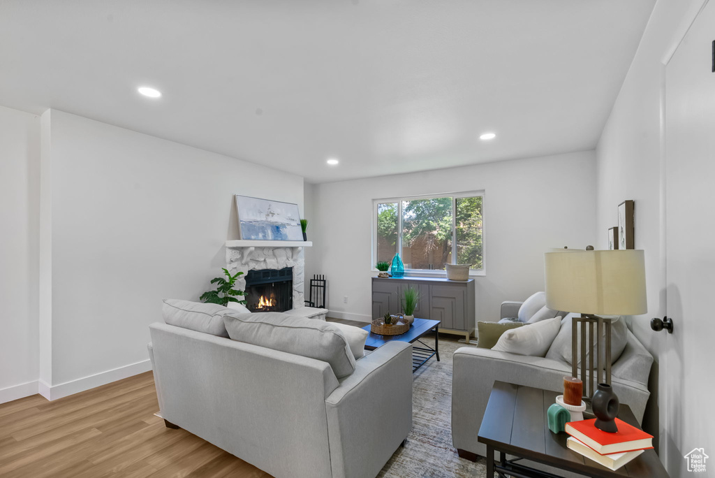 Living area with a stone fireplace, light wood-style floors, and recessed lighting