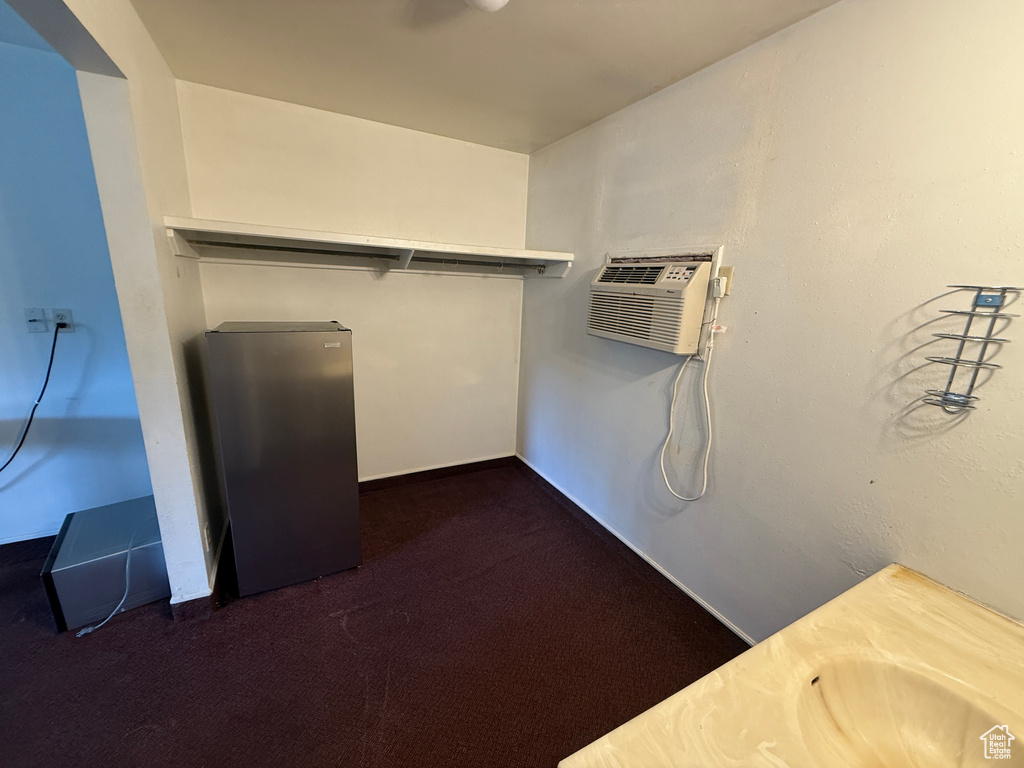 Spacious closet with dark colored carpet and an AC wall unit