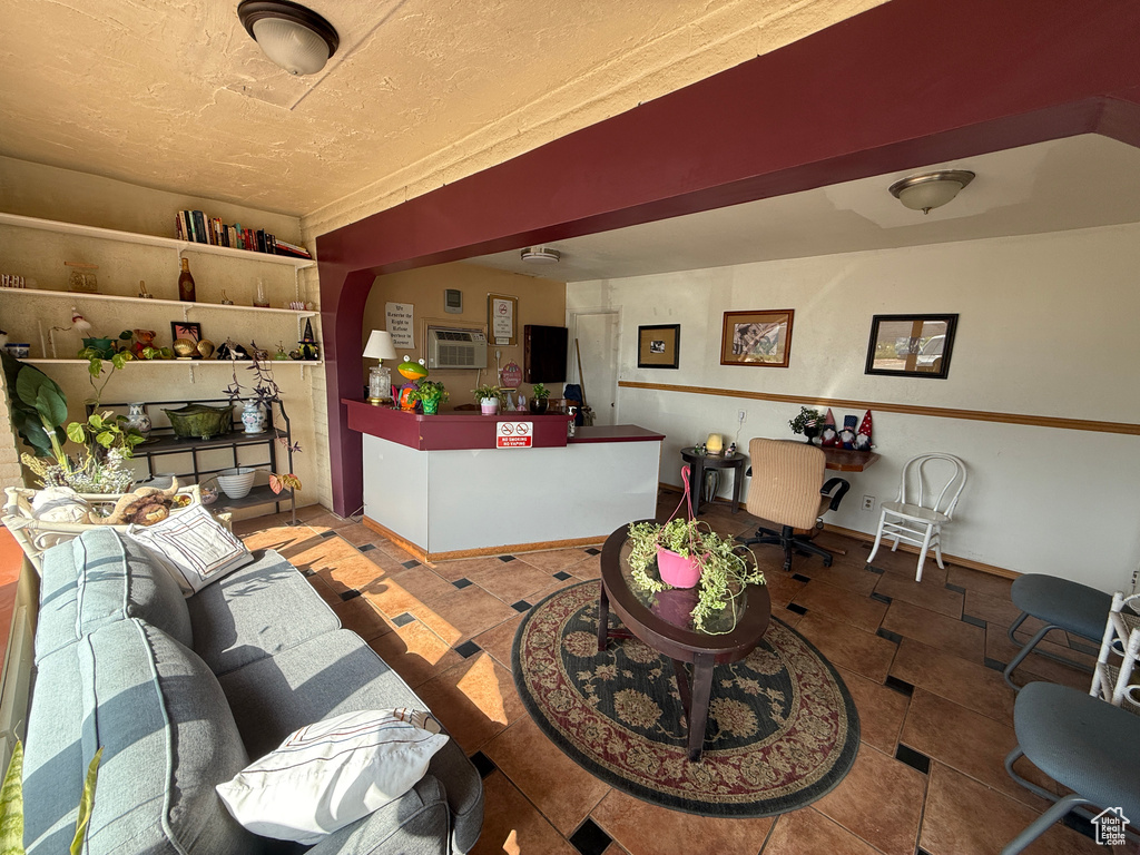 Tiled living area featuring a wall unit AC and baseboards