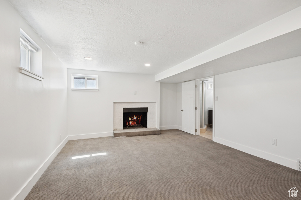 Basement featuring carpet floors, a brick fireplace, a textured ceiling, and recessed lighting