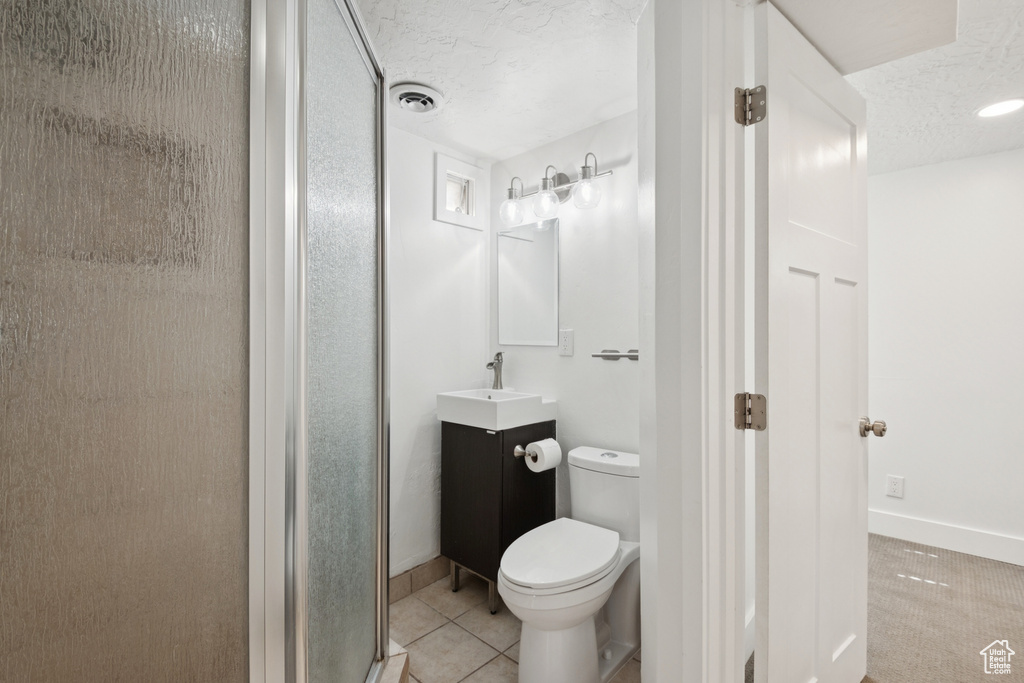 Full bathroom with vanity, a textured ceiling, a stall shower, and tile patterned flooring