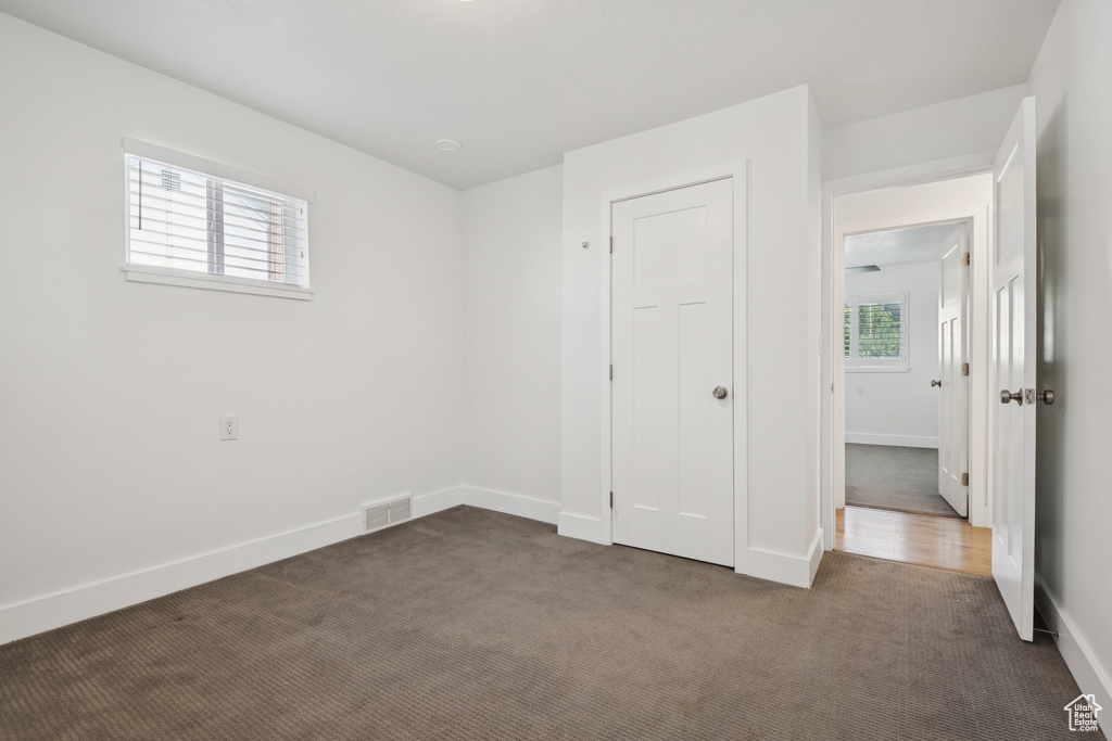 Unfurnished bedroom with dark colored carpet and baseboards